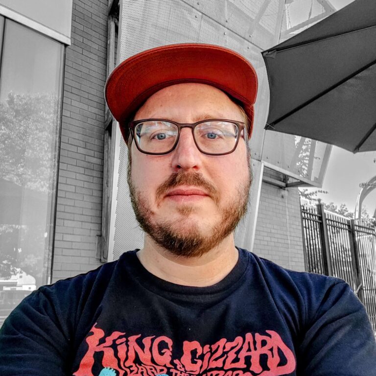Me, a white guy with glasses and short brown beard, wearing an orange cap and black t-shirt.